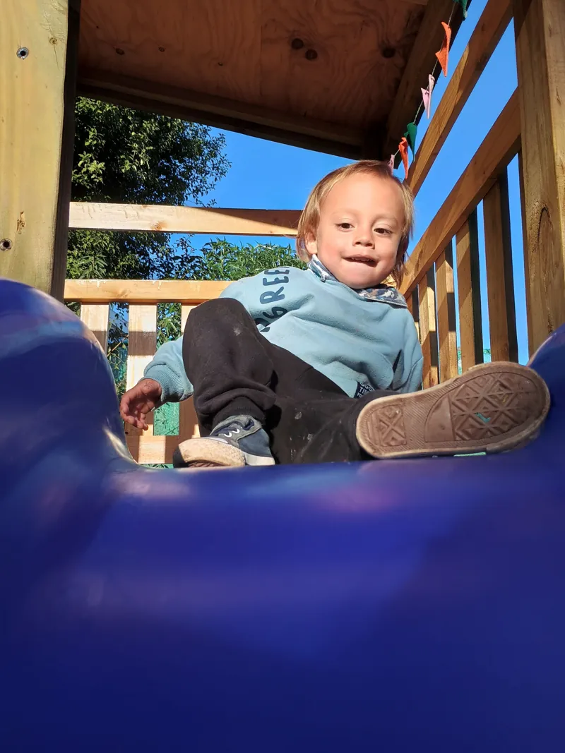 Un niño pequeño explora el resbalín del patio de Aurora.