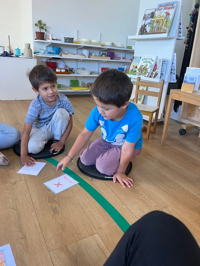 Dos niños se sientan juntos a trabajar en el ambiente de Aurora.
