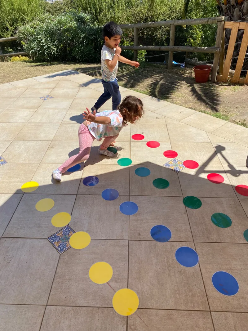 Niños participan en una actividad con círculos de colores en el patio de Aurora.