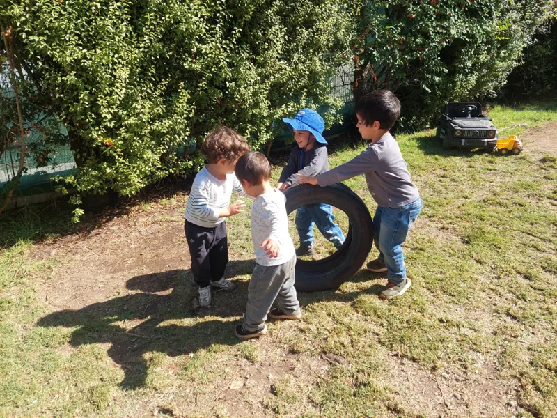 Niños juegan juntos con un neumático en el jardín de Aurora.