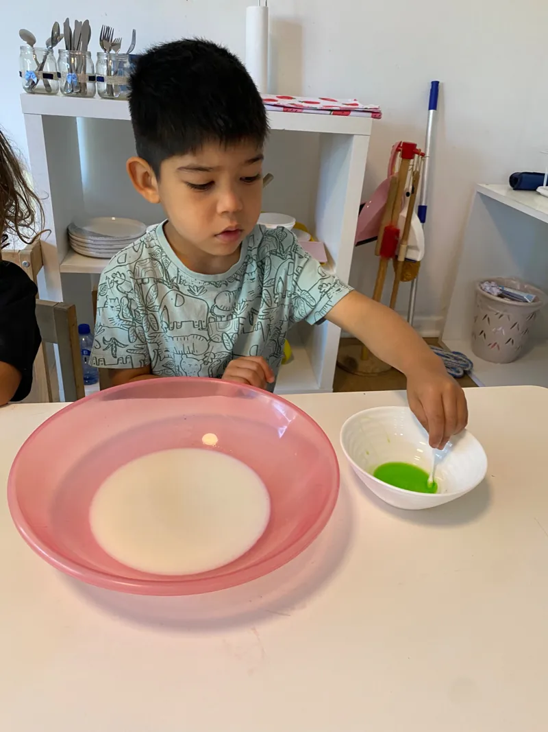 Un niño trabaja con una cuchara y pequeños recipientes en Aurora.