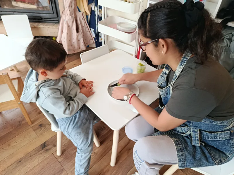 Una adulta acompaña a un niño en una actividad de mesa en Aurora.