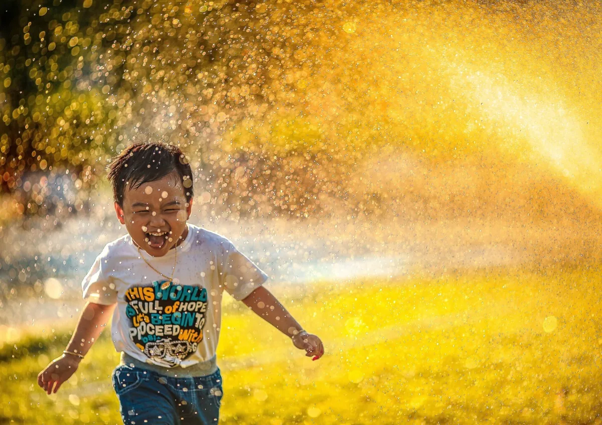 Un niño juega entre gotas de agua al aire libre.